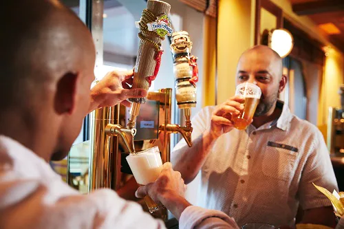 two men drinking thirstyfrog brews from a beer tap